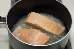 Salmon being poached in olive oil and water.